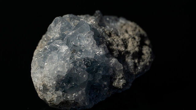 Closeup of sky blue celestine crystal gemstone on a reflective black surface