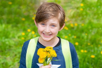 portrait of a happy smiling boy holding a bouquet of dandelions