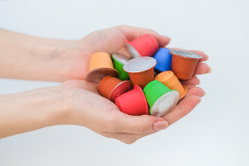 A woman holds coffee capulas in her hands and prepares espresso in a capsule coffee machine. White background. A bright room.