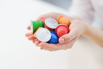 A woman holds coffee capulas in her hands and prepares espresso in a capsule coffee machine. White background. A bright room.