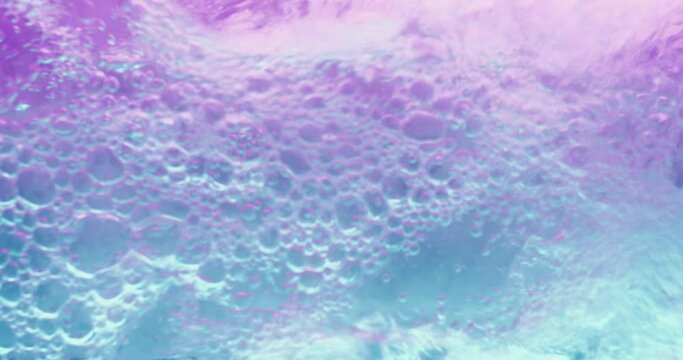 Water bubbles. Aqua splash. Foam wave. Neon iridescent clear liquid purple blue color soapy liquid pour flow motion on gradient abstract background shot on RED Cinema camera.