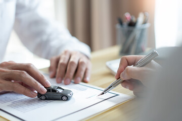 Insurance concept the customer signing his name on the contract while the dealer giving more details