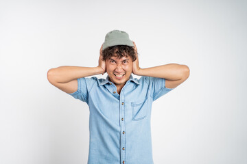 Stressed asian young man cover his ear does not want to hear anything over isolated background