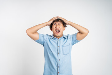 Stressed asian young man holding his head over isolated background