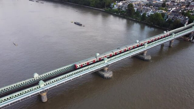 A drone view of a tube train on the Fulham Railway Bridge in London.