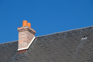Chimney on slate roof against clear blue sky © Avenue des Images