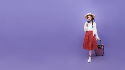 Smiling cheerful young woman tourist holding credit card for travel isolated on purple studio...