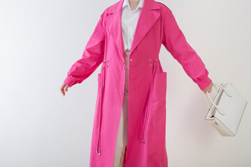  woman in pink trench coat with white handbag
