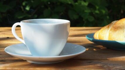 Coffee cup and fresh baked croissants, in a restaurant or cafe, smart phone on white background. Top View. girl preparing breakfast in the in the courtyard. a cup of coffee, watching the news