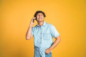 portrait of asian young man laughing while making phone call on isolated background