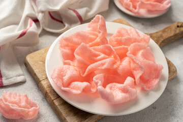 Shrimp chips in a white bowl on a light cooking table. Krupuk udang in a plate closeup
