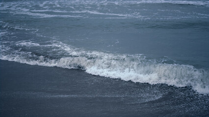 Blue water waves crashing coast background. Ocean foam splash in sea landscape.