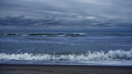 Blue waves crashing sea in dark storm sky. Powerful nature ocean landscape.