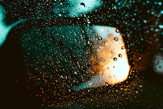Gotas de lluvia gotitas en el vidrio parabrisas del auto con luces desenfocadas