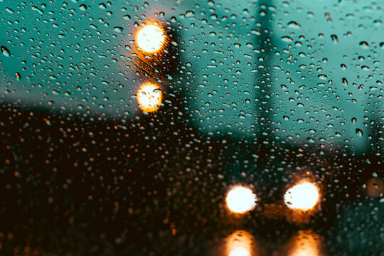 Gotas de lluvia gotitas en el vidrio parabrisas del auto con luces desenfocadas