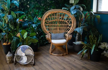 Tuinposter Bohemian stylish interior with peacock armchair, green plants in flowerpots and vintage boho details © Mykola