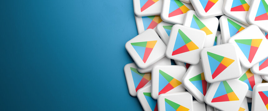 Logos of the Google Play app store for Android on a heap on a table. Copy space. Web banner format.