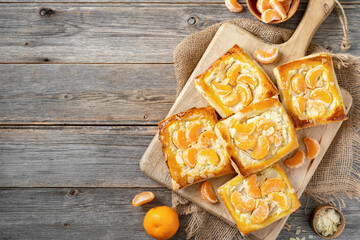 Mini puff pie with cheese cream, almonds, and tangerines in a plate on the kitchen table. Delicious...