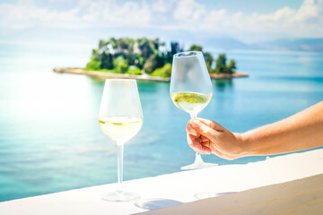Two glasses of white wine with Corfu in background