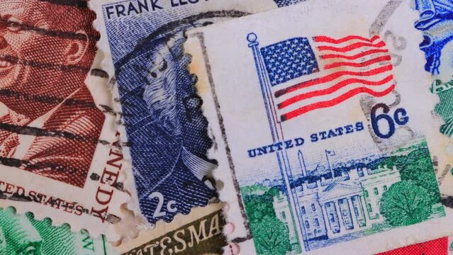 A collection of canceled US postage stamps. Vintage stamps showing portraits of statesmen who lived in USA. Close-Up Macro Moving Slider Shot of a Pile of American stamps