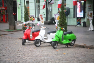 Obraz na płótnie Canvas three multi-colored scooters on the background of the building