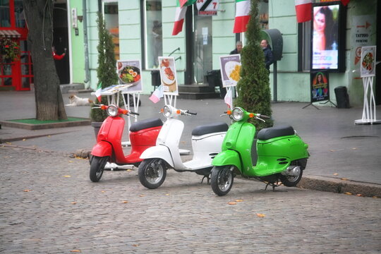 three multi-colored scooters on the background of the building