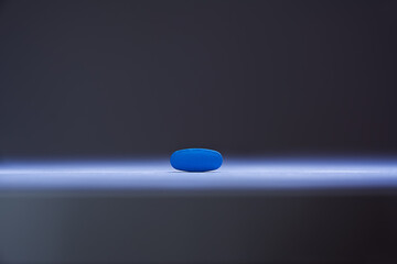 Single blue pill illuminated by a single sharp beam