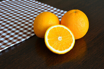 oranges on dark wooden table with tablecloth on background