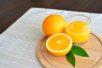 fresh orange juice in glass with orange fruits on beige background