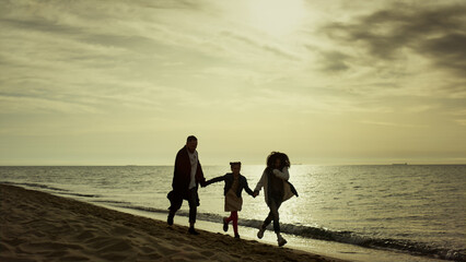 Young family running sea shoreline. People having good time together at beach.