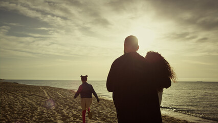 Lovely family looking sunset ocean beach. Mom dad child walking beautiful coast. © stockbusters