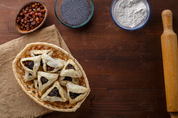 Gomentash with poppy seeds and prunes freshly baked for the Purim holiday on a wooden table on a napkin