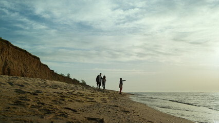 Parents child enjoy sea waves on sand beach. Family loving ocean coast vacation.
