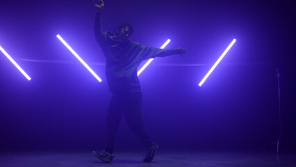 Dancer performing hip hop nightclub. Silhouette b-boy making agile movements.
