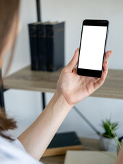 Online education. Digital mockup. Mobile connection. Unrecognizable woman holding smartphone with blank screen in hand light room interior.