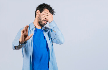 Scared confused man closing eyes with palm of hand