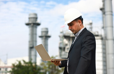 Business man or senior engineer work on notebook at site line of Cogeneration Power Plant, Industrial and business investment