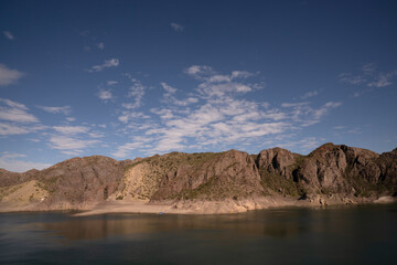 View of the lake and rocky hills in the desert under a deep blue sky. 