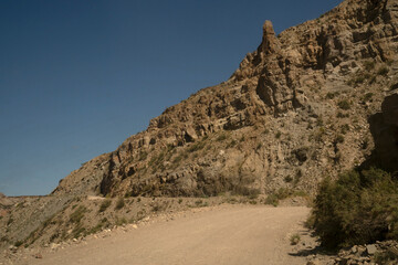 Traveling in the desert. View of the dirt road across the arid sandstone and rocky mountains. 