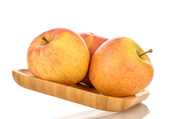 Three sweet ripe apples on a bamboo tray, close-up, isolated on a white background.