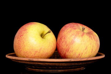 Two sweet ripe apples with a clay plate, close-up, isolated on a black background.