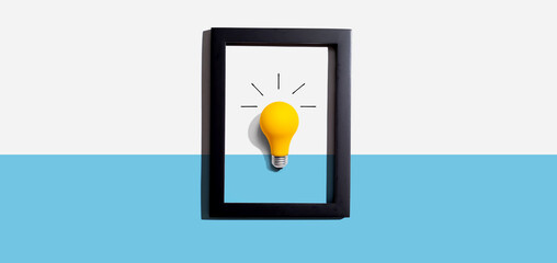 Yellow light bulb inside a frame - inspiration, creativity, energy, electricity themes