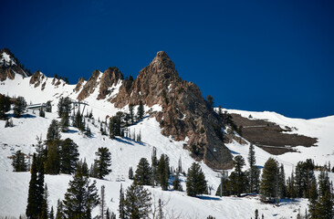 Beautiful landscape at Snowbasin Ski Resort, Utah. Snow slopes, rocky mountains and trees on a sunny day.