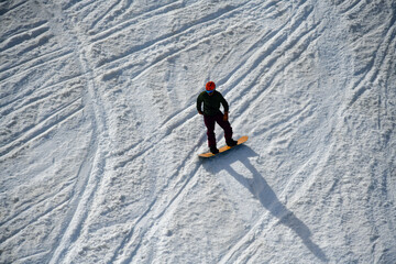 Snowboarder downhill at Snowbasin Ski Resort in Utah. Early spring weather conditions.
