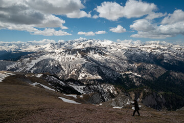 a girl walks on the slopes of snow-capped mountains and beautiful clouds
