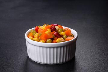 A mixture of chopped vegetables paprika, corn, peas in white plate