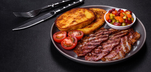 Slices of delicious grilled bacon with croutons fried in egg with spices, salt, vegetables and herbs