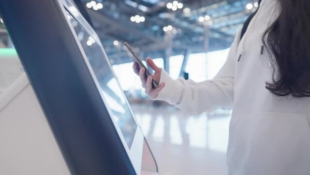 Passenger using smartphone scanning qr code on the ticket machine to check in for the flight at the airport terminal, less contact new normal technology, Screen scanner redeem ticket, online booking