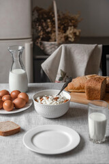 At home, in the kitchen, the table is covered with a linen tablecloth and there are natural and healthy products, milk and cottage cheese, bread and boiled chicken eggs on it