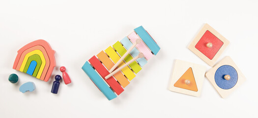 Baby kids toys. Top view to colorful educational wooden toys arranged on white background. Early education for kids. Learning music for children. Educational Montessori toys - obrazy, fototapety, plakaty